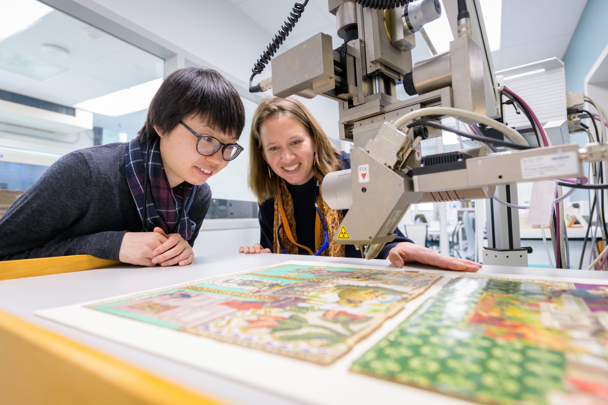 Dr. Rosie Grayburn (right) and graduate student Yan Ling Choi examine the elemental composition of the pigments on “Helen’s Scrapbook House,” using non-destructive X-ray fluorescence analysis.